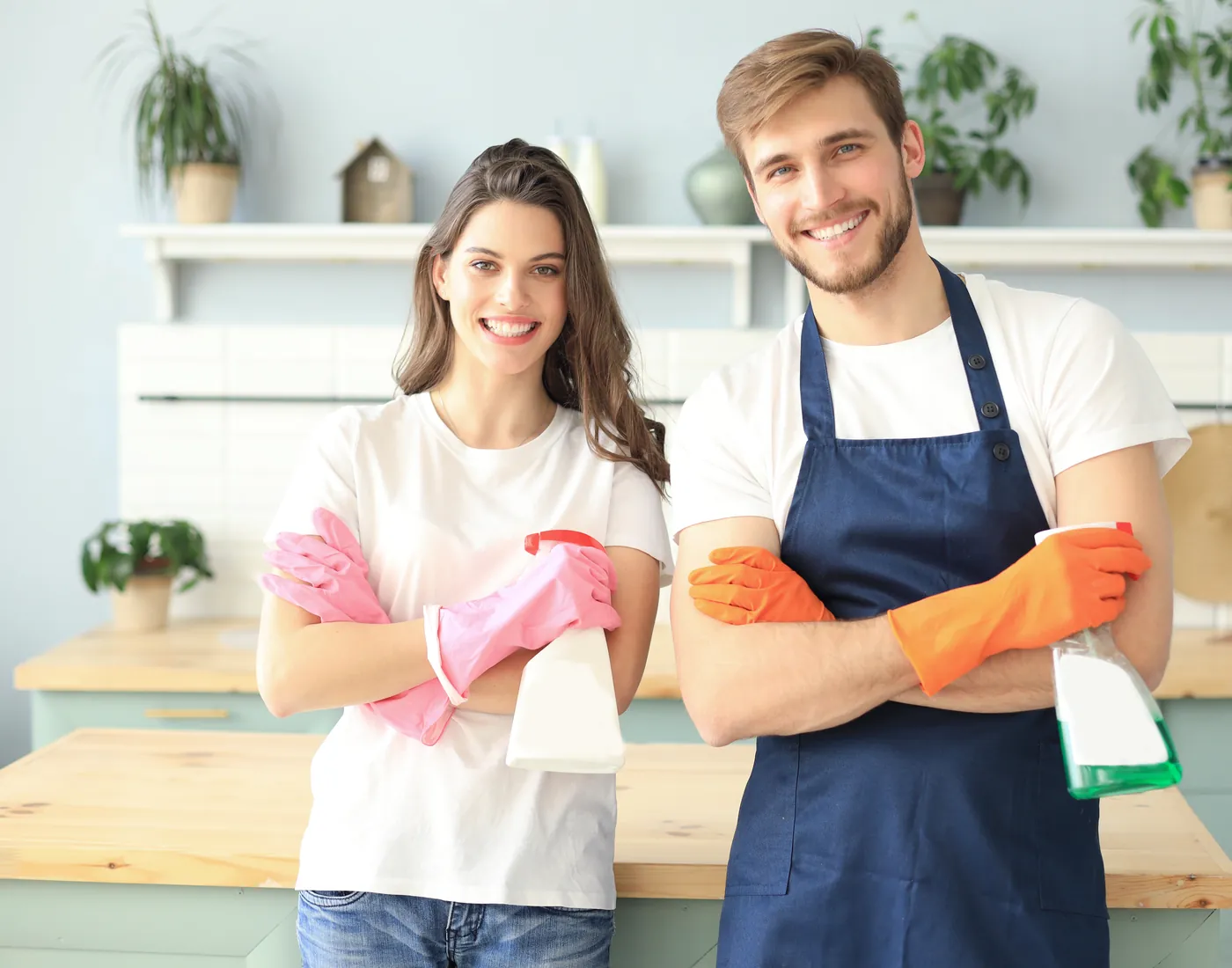 Smiling couple of cleaning professionals with gloves and spray bottles in a kitchen in Orlando