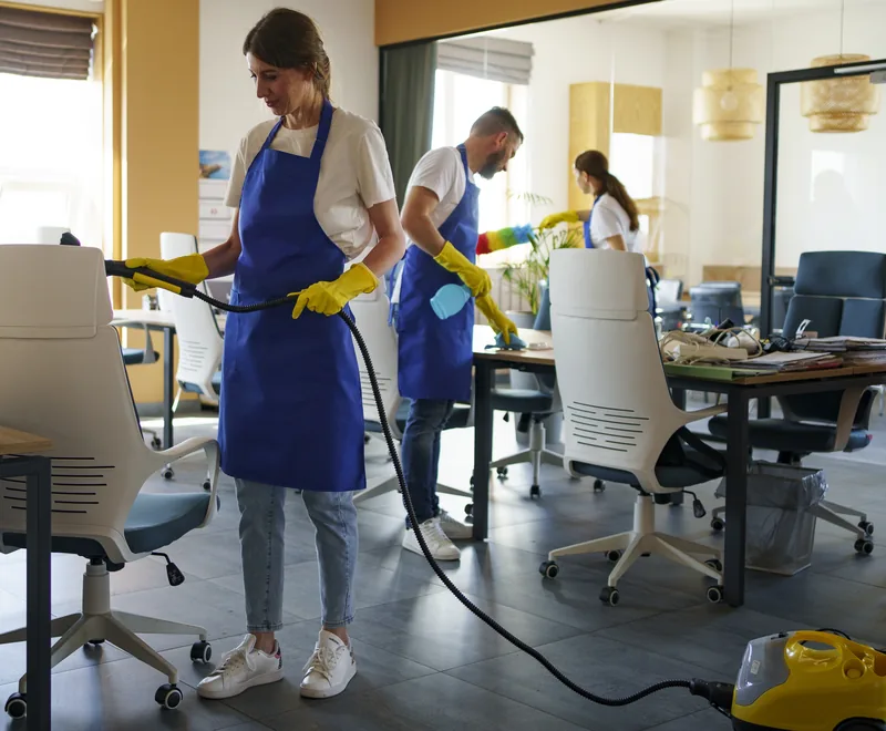 Cleaning team in blue aprons vacuuming and cleaning an office in Orlando